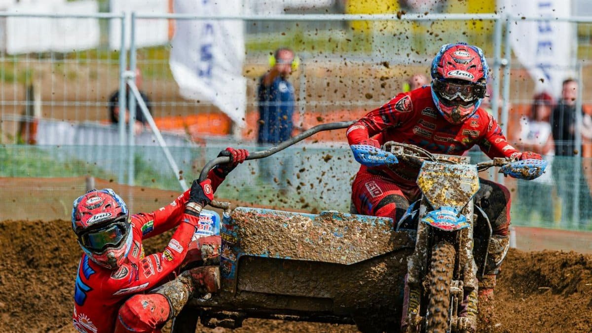Dynamic sidecar motocross race with riders in action on a muddy track, showcasing skill and speed.