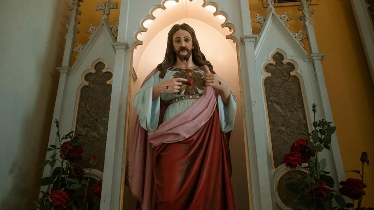 A religious statue of the Sacred Heart of Jesus within a church setting, symbolizing faith and devotion.