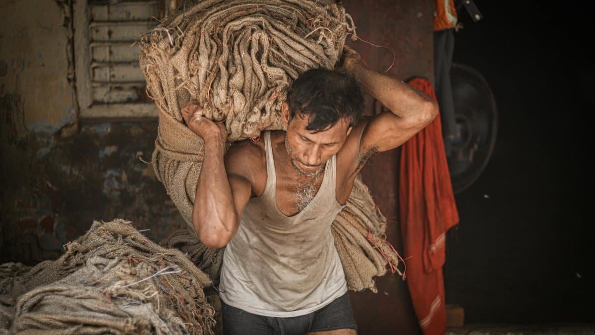 A man in Ballia, India, carrying heavy fabric bundles, showcasing hard work and determination.
