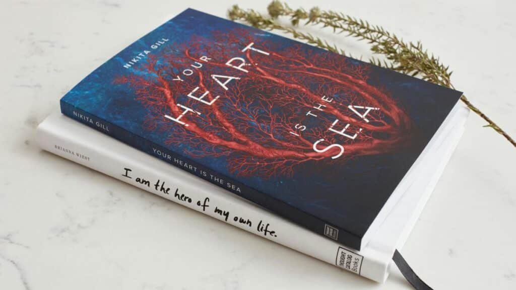 Close-up of two books stacked on a marble surface with a decorative branch.