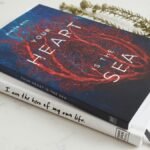 Close-up of two books stacked on a marble surface with a decorative branch.