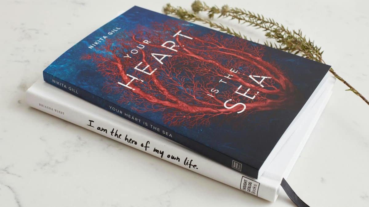 Close-up of two books stacked on a marble surface with a decorative branch.