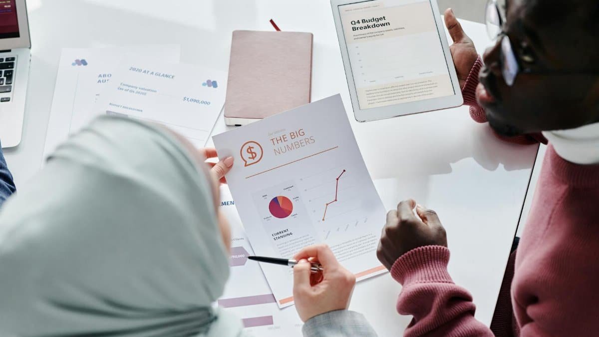 Two colleagues reviewing financial documents and graphs during an office meeting.