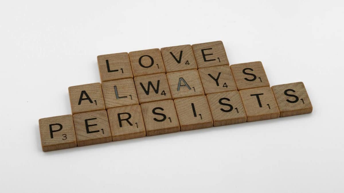 Scrabble tiles on a white background form the phrase 'Love Always Persists', emphasizing a message of enduring love.