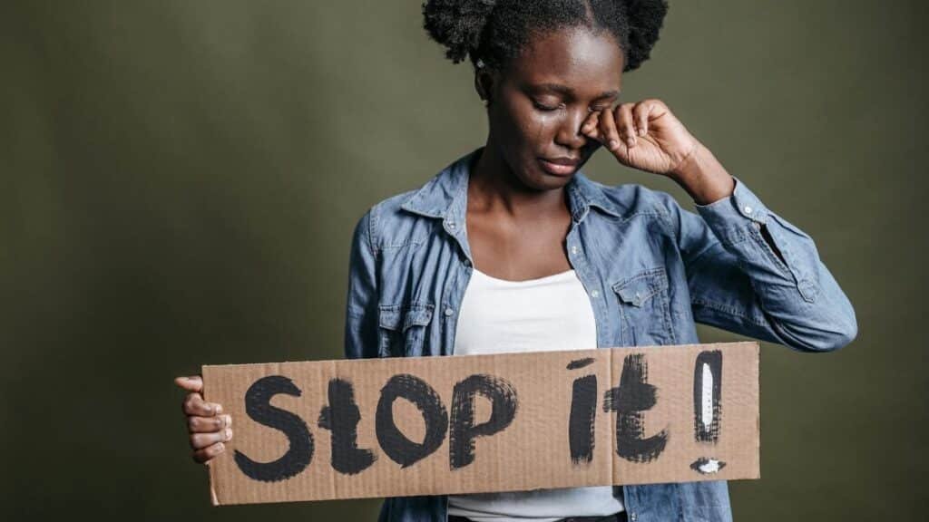 A woman tearfully holding a 'Stop it!' sign against racism in a powerful protest image.
