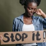 A woman tearfully holding a 'Stop it!' sign against racism in a powerful protest image.