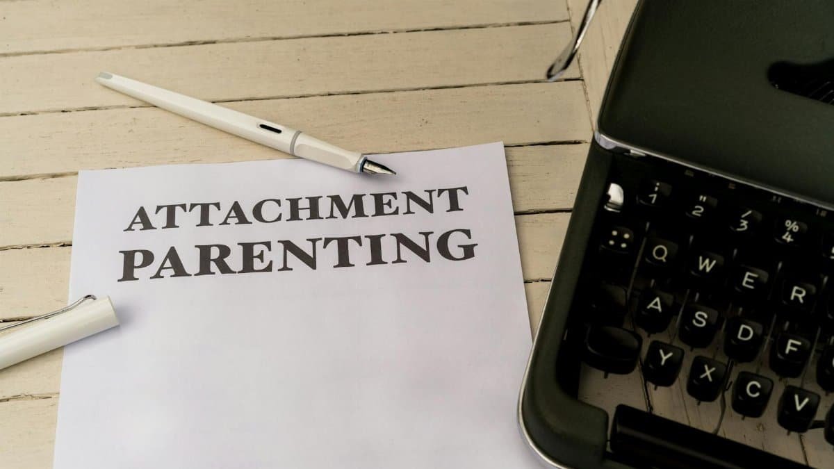 Vintage typewriter and paper with 'Attachment Parenting' text on wooden desk.