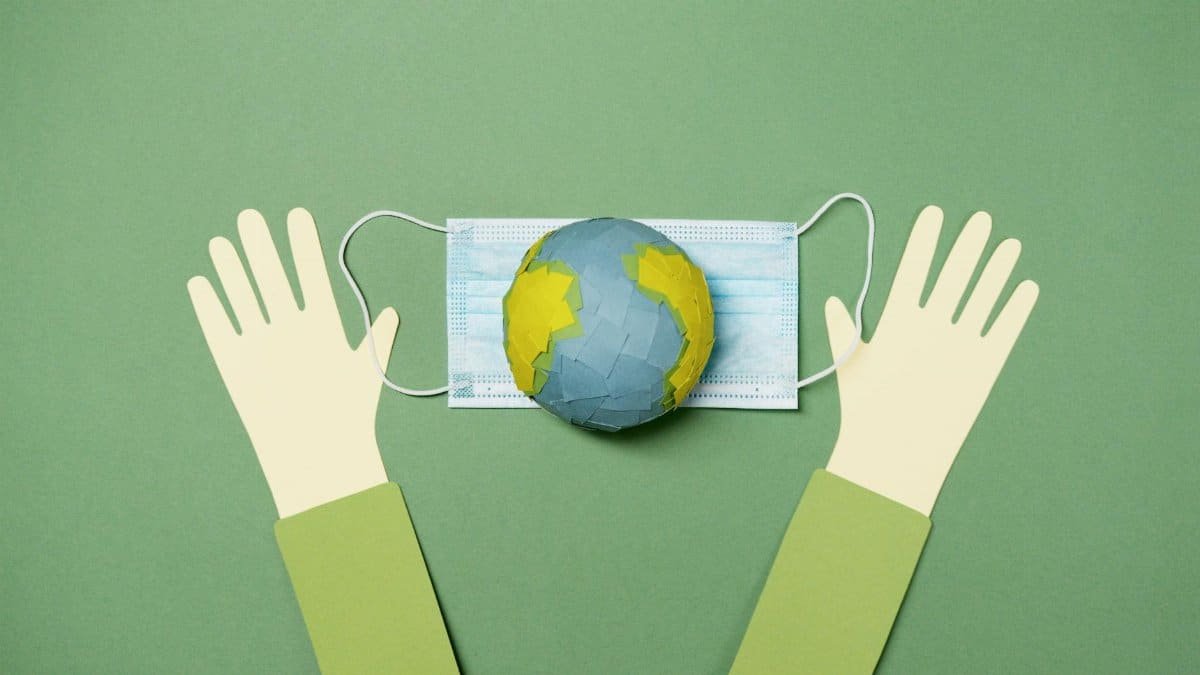 Creative image showing a paper-cut Earth on a mask with hands, symbolizing global protection.