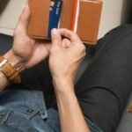 Over-the-shoulder view of a person holding a leather wallet displaying credit cards.