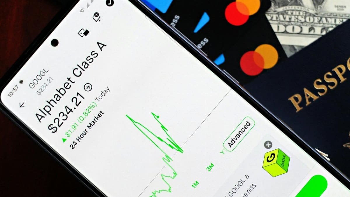 Smartphone displaying stock market app next to U.S. dollar and passport, representing global finance.