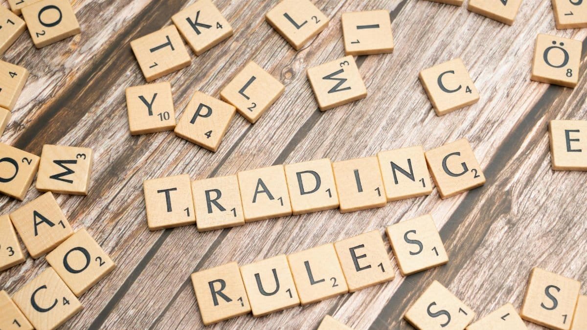 Wooden letter tiles arranged to spell 'Trading Rules' on a wooden surface.