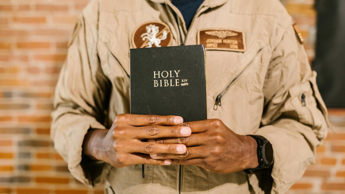 Military veteran in uniform holding the Holy Bible, symbolizing faith and spirituality.