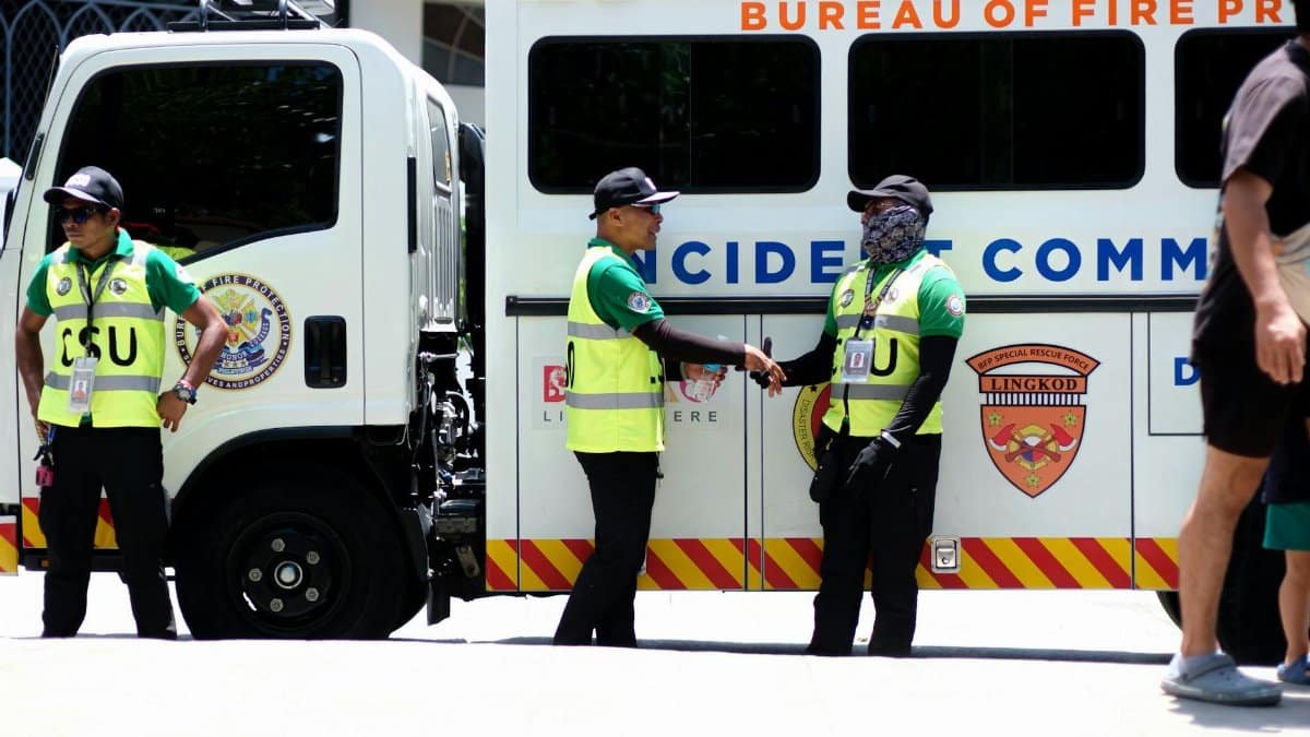 Security officers in safety vests beside an emergency response vehicle.
