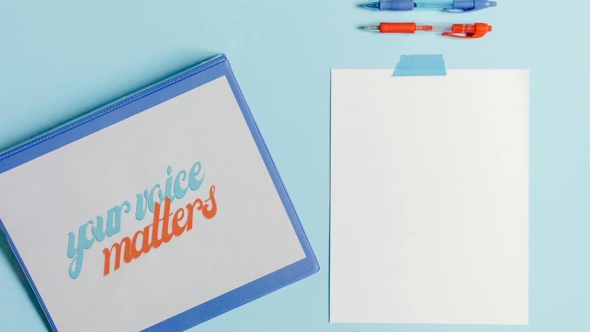 A flat lay of pens, paper, and 'Your Voice Matters' document on a blue background.