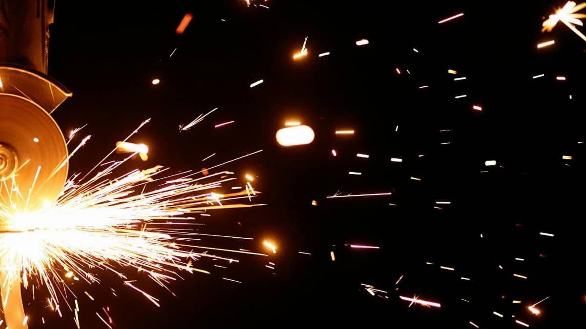 Close-up of vibrant sparks from an angle grinder against a dark background.