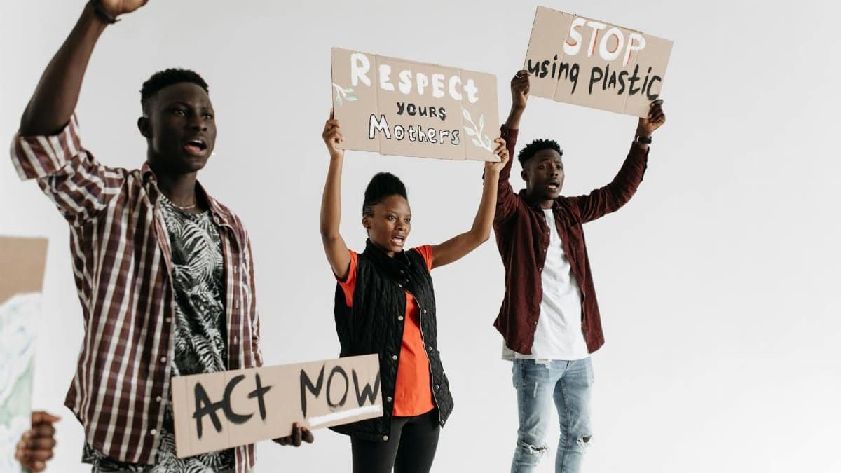 Young adults holding protest signs advocating for respect and environmental awareness.