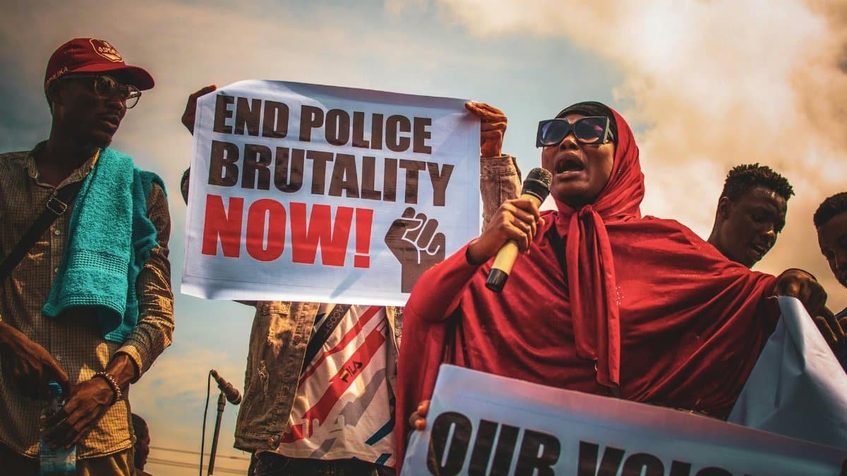 Nigerian activists holding signs urging to end police brutality during a peaceful outdoor protest.