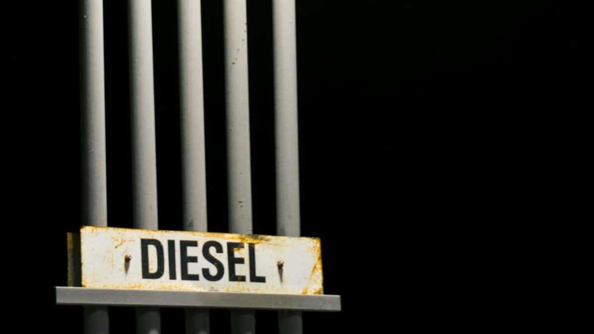 Diesel fuel sign on metal pipes against a dark black background at night.