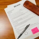 Flat lay of divorce papers with a pen and ring on a wooden table for legal themes.