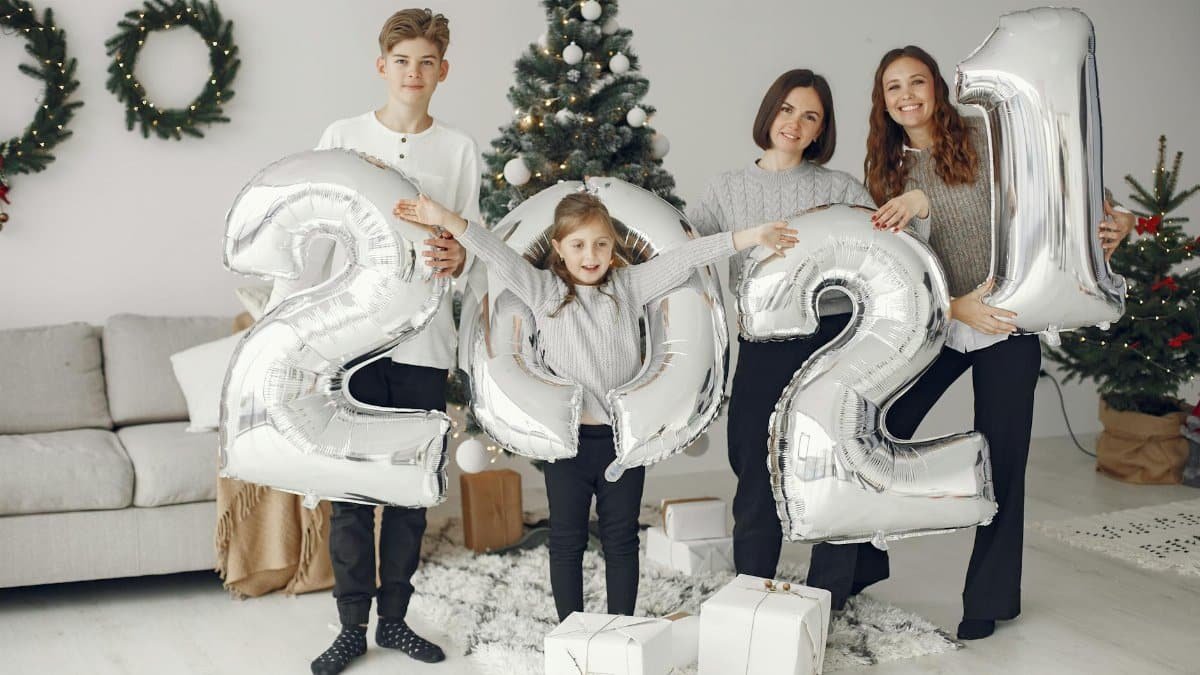 Joyful family celebrating New Year 2021 at home with balloons and gifts.