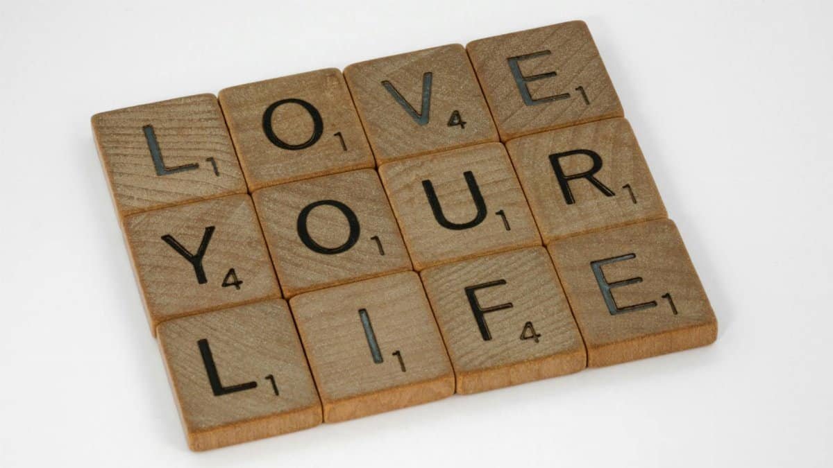Scrabble tiles arranged to spell 'Love Your Life' against a white background, conveying a positive message.