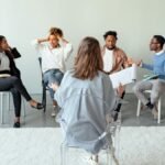 People engaging in a group therapy session indoors, discussing mental health topics.
