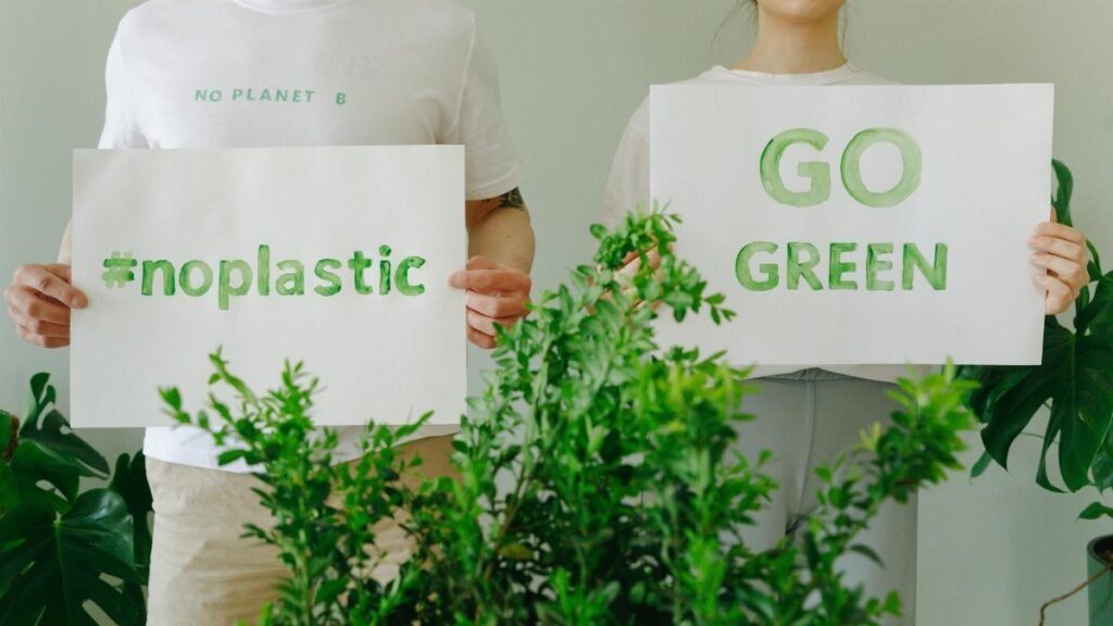 Two people holding eco-friendly signs promoting sustainability and going green.