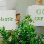 Two people holding eco-friendly signs promoting sustainability and going green.