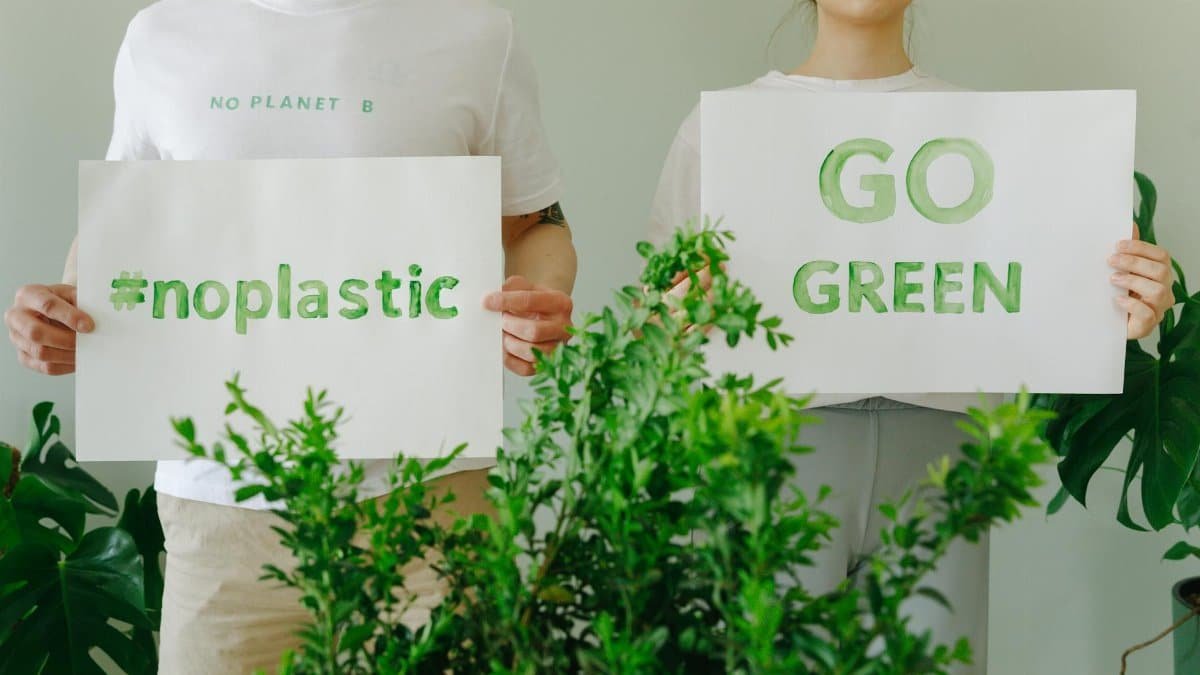 Two people holding eco-friendly signs promoting sustainability and going green.