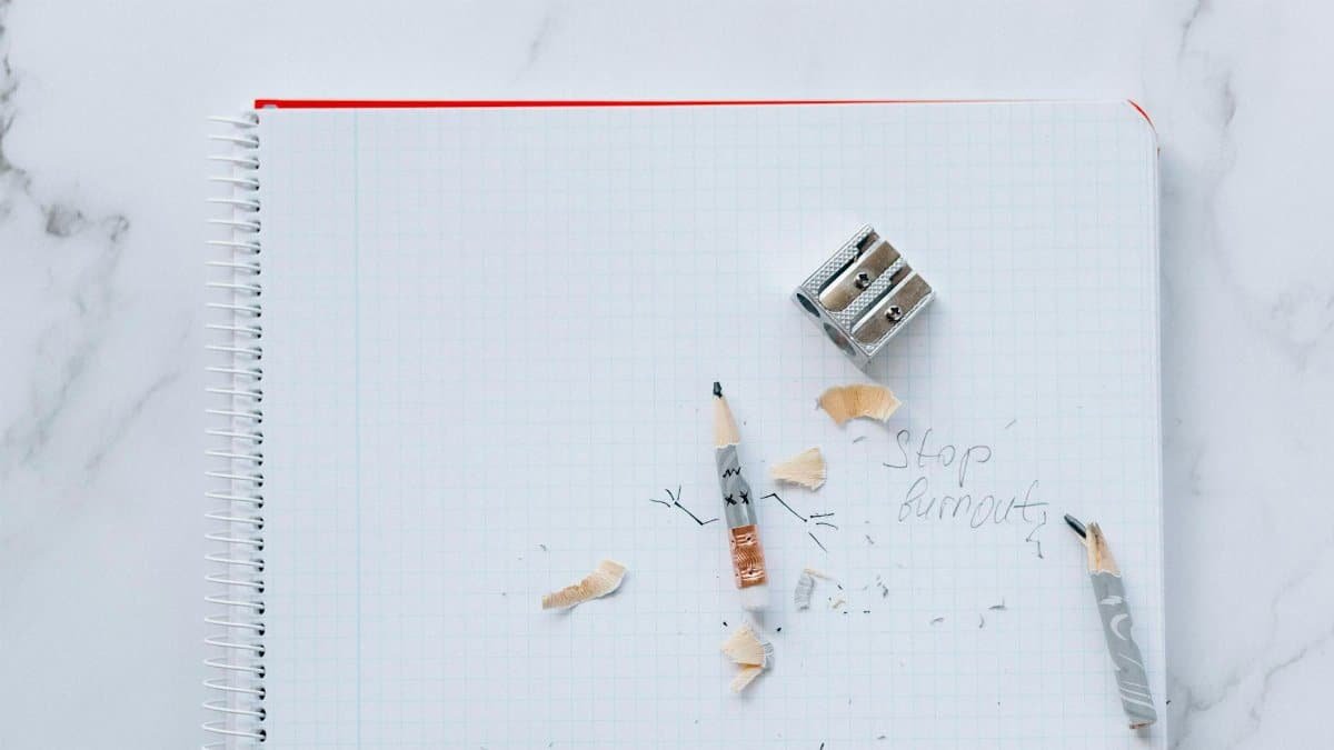 Spiral notebook with pencils, sharpener, and 'Stop burnout' written on paper.