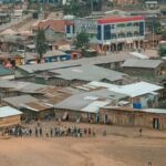 Aerial view of a lively community scene in an African town with colorful buildings.