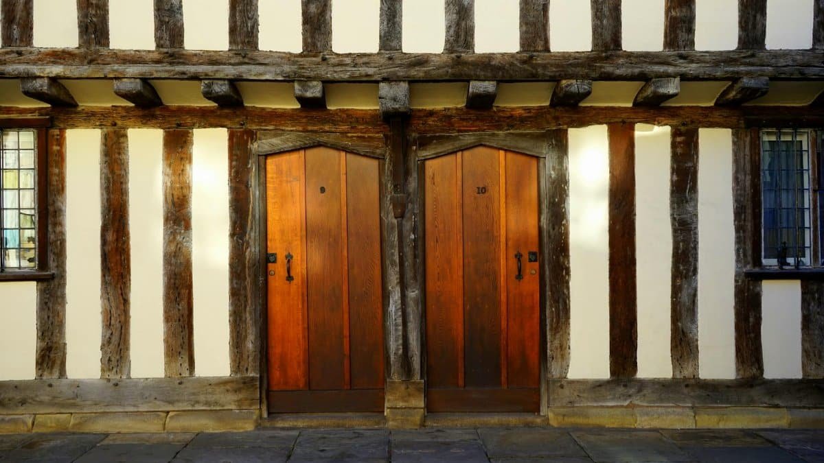 Traditional Tudor-style wooden doors framed by timber beams in Warwickshire, UK.