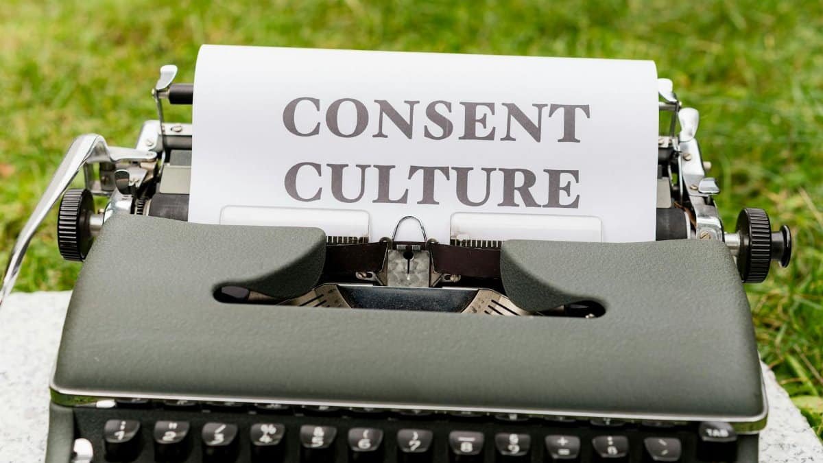 Close-up of a vintage typewriter with 'Consent Culture' typed on paper, set outdoors.