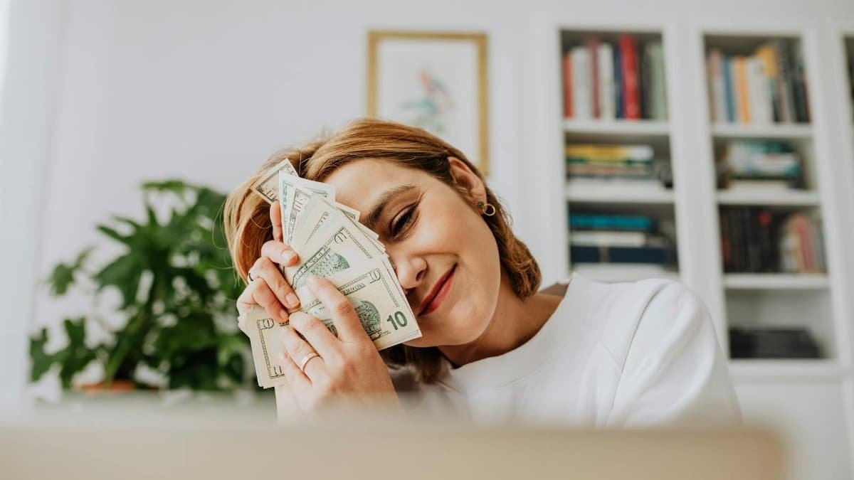 Happy woman with dollar bills, symbolizing financial success and fulfillment.
