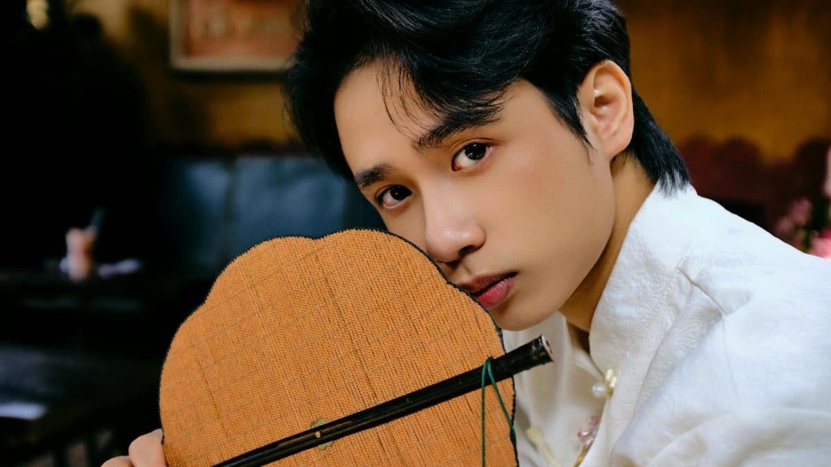 A man in a white ao dai poses indoors, evoking Lunar New Year vibes.