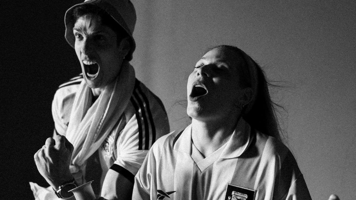 Excited sports fans cheer passionately, capturing the thrill of the game in a black and white photo.
