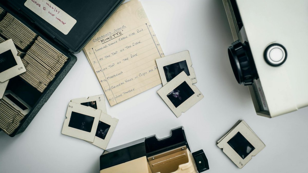 Flat lay of vintage slide projector and film slides, capturing nostalgia in photography.