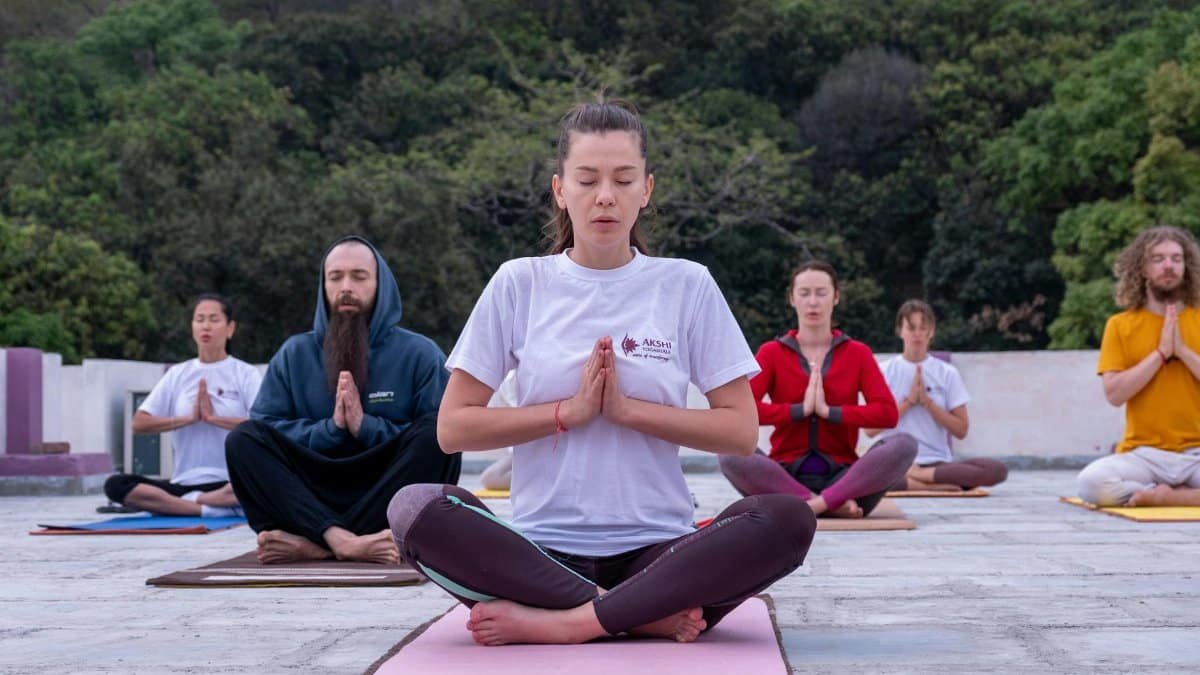 A diverse group practicing meditation outdoors in a serene environment.