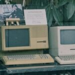 Retro Apple computers with keyboards displayed in a Tokyo store window, showcasing early tech design.