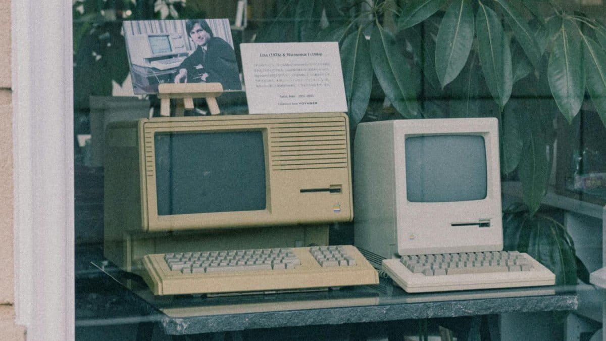 Retro Apple computers with keyboards displayed in a Tokyo store window, showcasing early tech design.