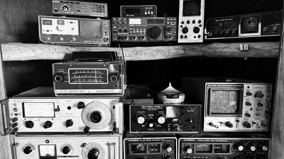 A black and white display of vintage radio devices on a rustic wooden shelf in Werribee, Australia.