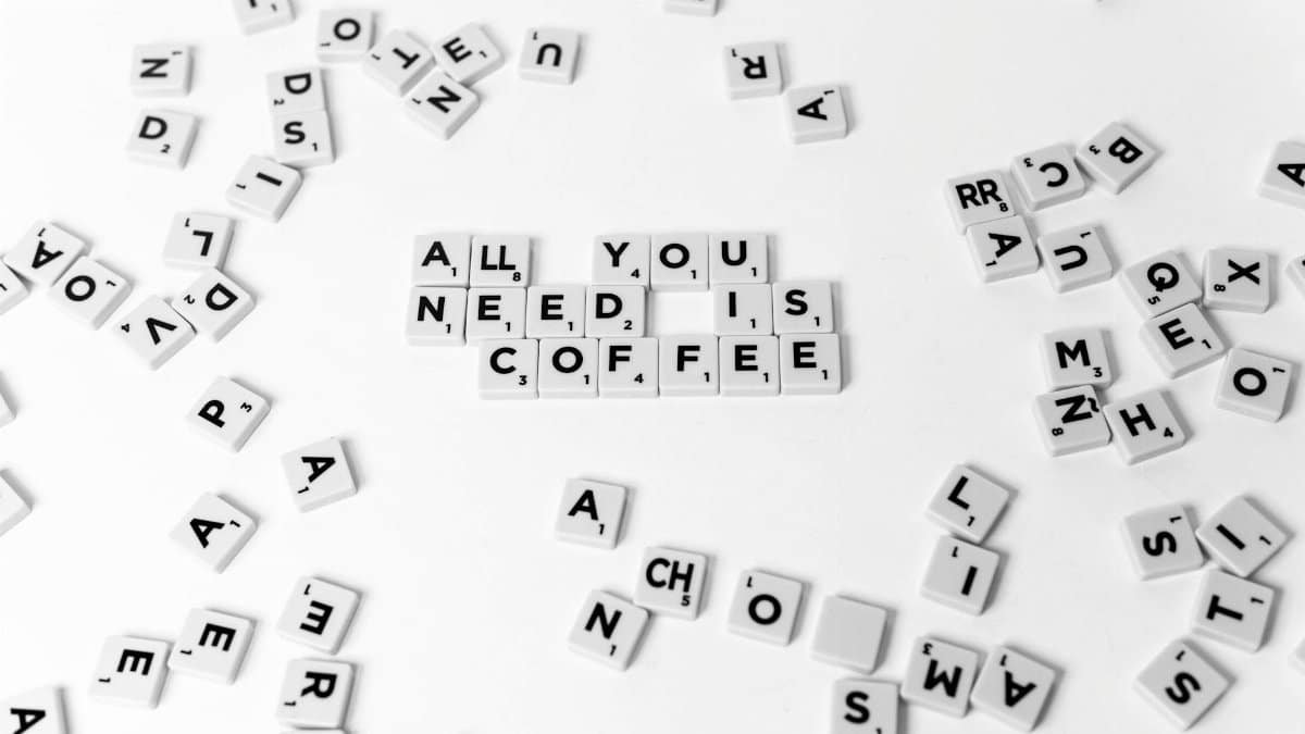 Scrabble tiles arranged to say 'All You Need is Coffee' on a white background.