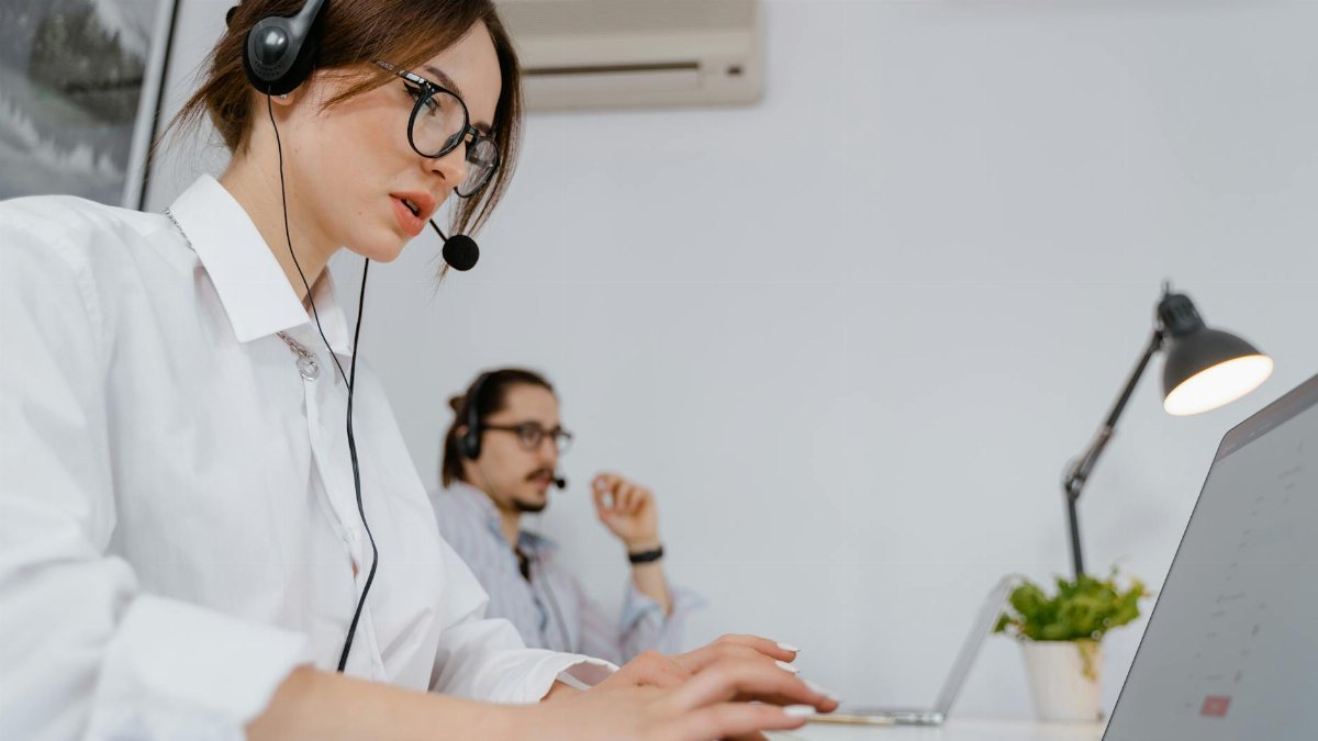 Focused customer support professionals working in a modern office with headsets and laptops.
