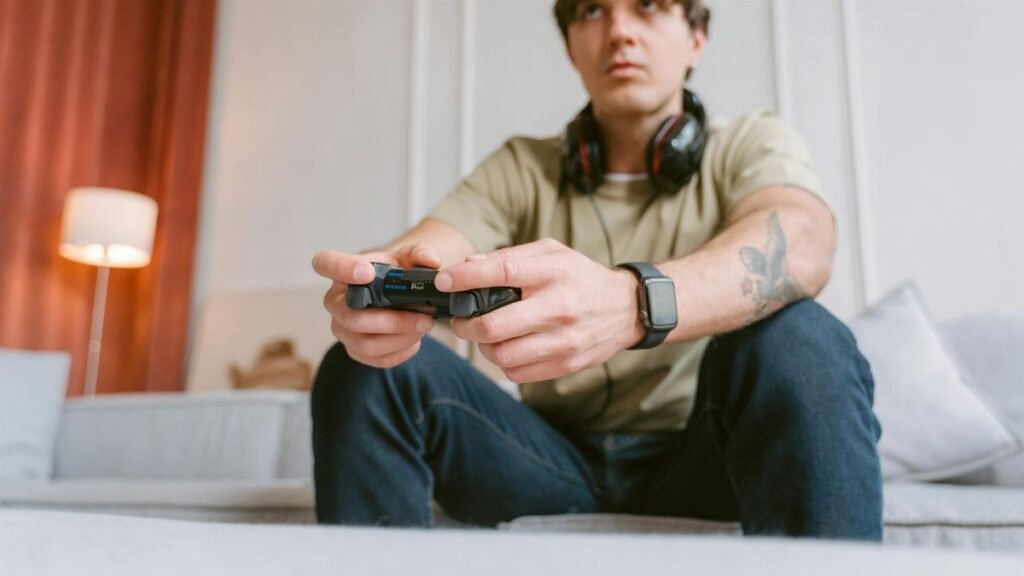 Young man focused on video gaming at home wearing headphones and a smartwatch.