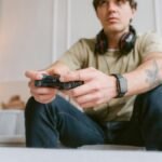 Young man focused on video gaming at home wearing headphones and a smartwatch.