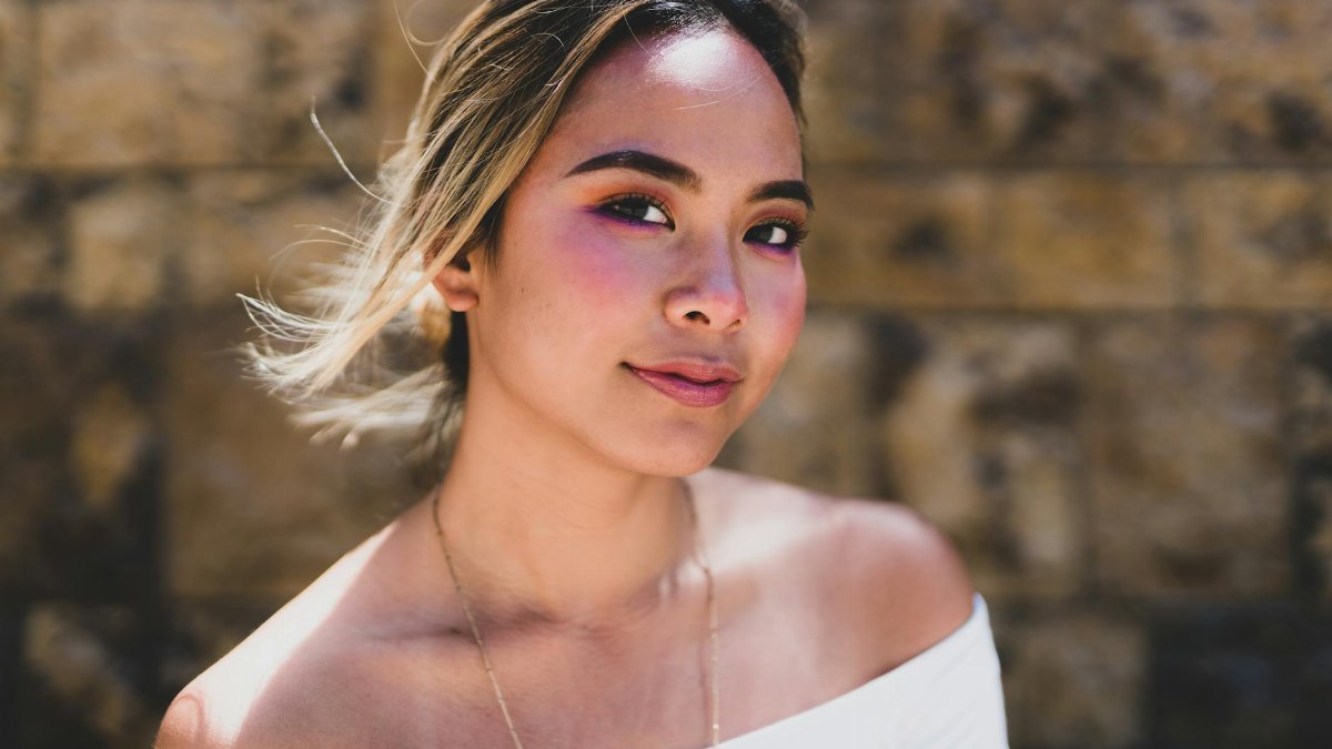 Glamorous portrait of an Asian woman against a textured wall in Los Angeles.