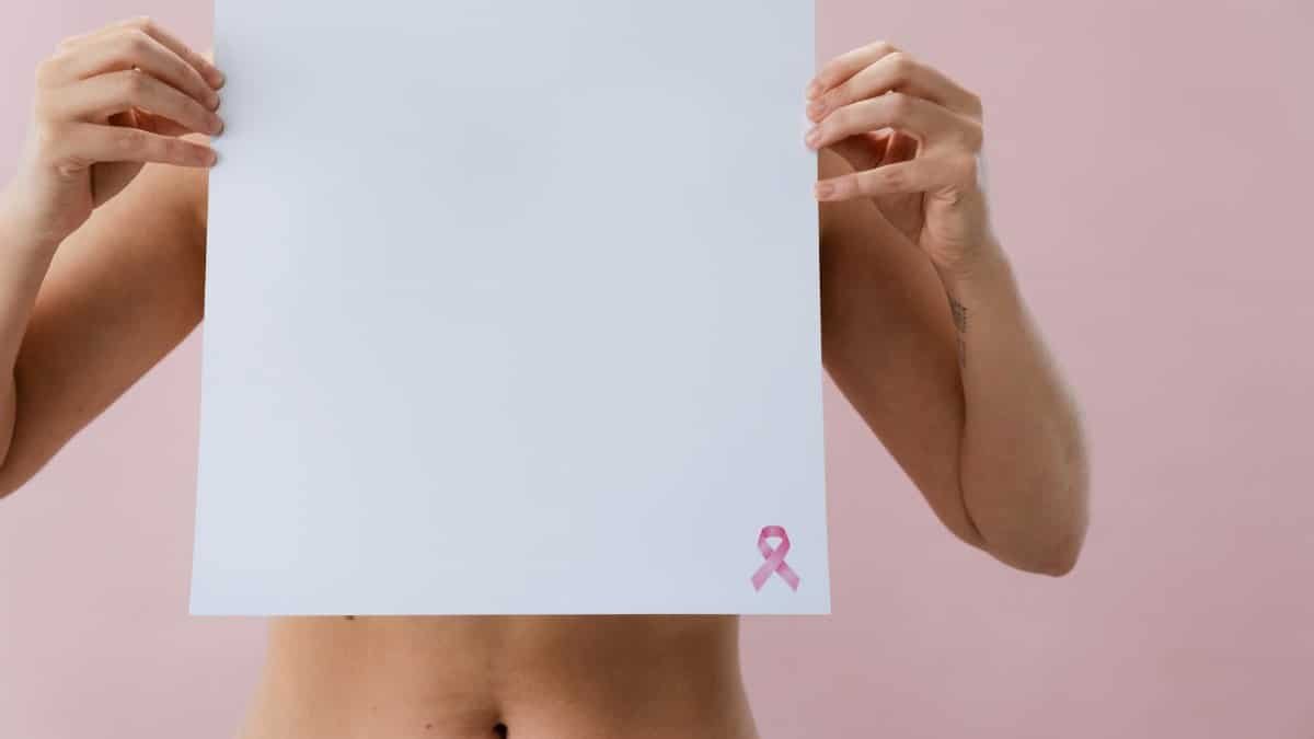 Image of a woman holding a blank paper with pink ribbon for breast cancer awareness.