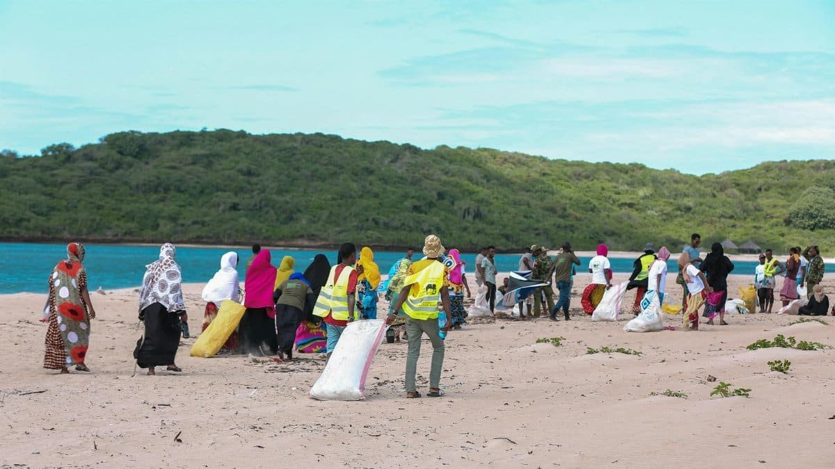 A diverse group participates in a community beach cleanup in Lamu, Kenya.