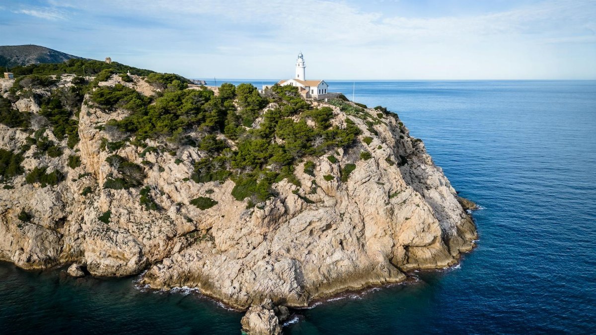 Aerial shot of the picturesque Far de Capdepera Lighthouse on a rocky island overlooking the sea.
