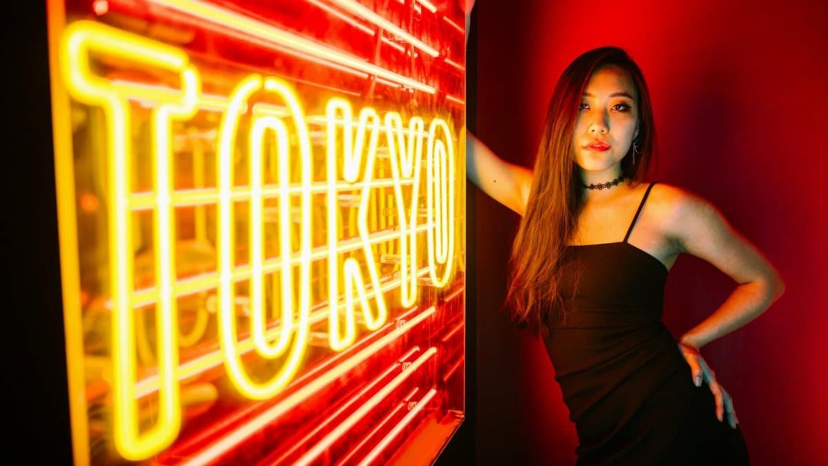 A stylish woman poses by a vibrant Tokyo neon sign, exuding modern urban nightlife.